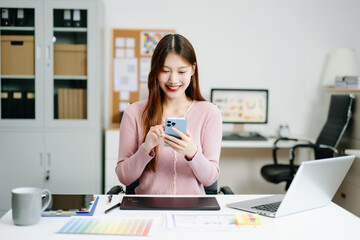 Young female graphic designer using digital tablet and laptop in modern office. Creative workspace,...
