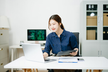 Young female programmer working with tablet and screen displaying code. Modern tech office setup, great for software, coding, IT