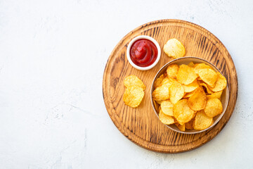 Potato chips in wooden bowl on white table. Top view.