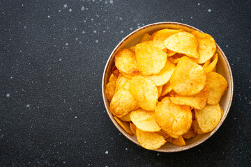 Potato chips and ketchup on black table. Top view.