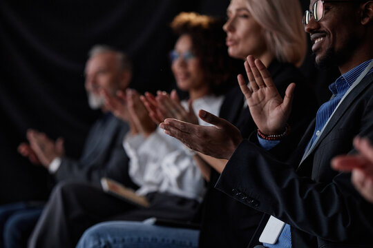 Cropped shot of smiling Black man applauding motivational speech while attending professional business conference in auditorium, selective focus on hands