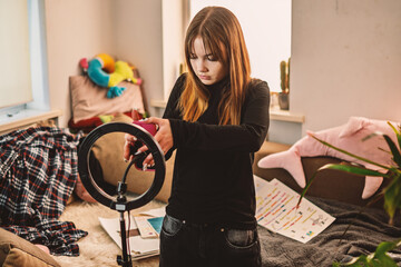 Teen girl recording online video in her room using ring light at home