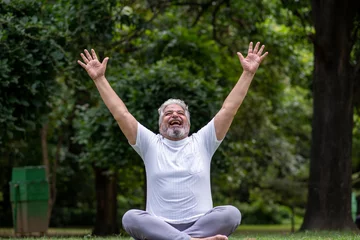 Fotobehang Ontspanning Happy senior indian man laughing spreading hands, relaxing doing yoga at park. Retirement life. Mental health and fitness, Stress free, Fun activity. laugh of therapy senior living   © Pix4Ads