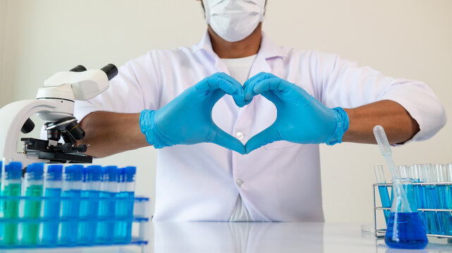 cardiac surgeon wears blue gloves and makes heart hand sign to show his full care and attention to heart disease patients as surgeon. Heart hand sign made by surgeon while wearing blue medical gloves
