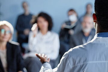 Rear view of African American male physician presenting at meeting with colleagues while...