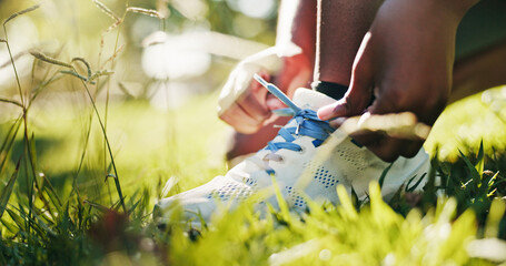 Fitness, hands and tie shoes on grass to start exercise, workout preparation and park training. Athlete, person and getting ready with sneakers in nature for cardio, running performance and wellness