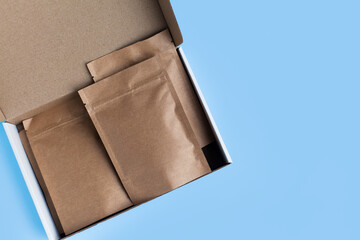 Kraft brown paper empty bags isolated mock up on light blue background. Eco friendly pack with zipper, roasted specialty coffee beans, tea, snack, alternative sample trendy concept. top view, flat lay