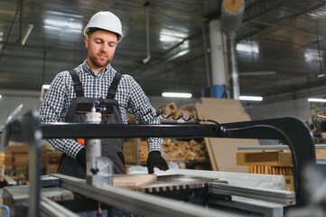 Carpenter operating cnc woodworking machine in furniture factory