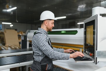 Carpenter operating cnc machine in furniture factory