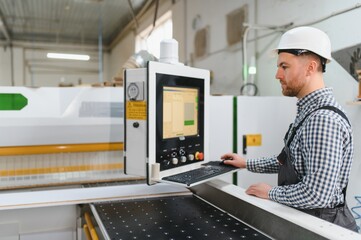 Carpenter operating cnc machine in furniture factory