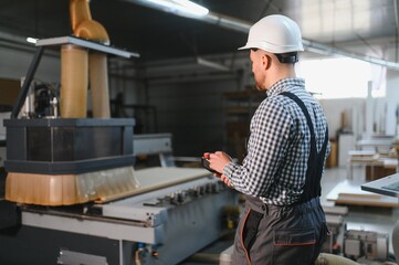 Carpenter operating cnc machine in furniture factory