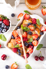 Summer fruit and berry french Toast baked Casserole. Homemade hot tasty delicious french Toast baking, breakfast cake with cream, toast bread and fresh strawberry, blueberry, raspberry and cherry