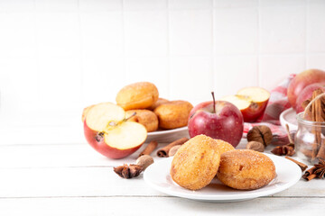 Tasty homemade apple pie autumn tasty donuts with cinnamon sugar glazing and apple jam filling, with fresh apples and spices on white wooden background copy space