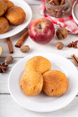 Tasty homemade apple pie autumn tasty donuts with cinnamon sugar glazing and apple jam filling, with fresh apples and spices on white wooden background copy space