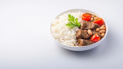 A delicious bowl of white rice is presented alongside a hearty beef stew with beans and bright red tomatoes garnished with parsley on a clean white backdrop.