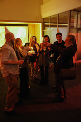 A group of six employees stand and have fun while holding glasses, one of them holding a cake, in a hall
