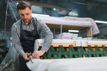 Carpenter working on sofa frame in furniture factory