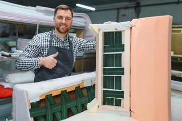 Carpenter showing thumb up near sofa frame during furniture production