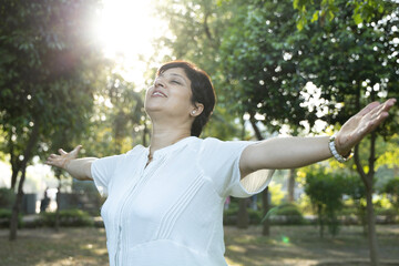 Indian happy senior woman spread her arms in environment nature like the wings of a bird....