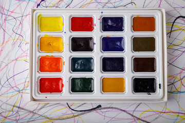open box of multicolored watercolor paints on paper background
