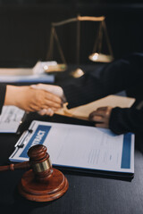 Two lawyers shaking hands after reaching an agreement during a legal trial, with scales of justice and gavel in the foreground