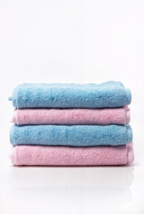Stack of soft blue and pink towels on white background