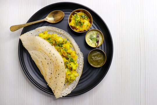 Crispy Masala dosa is a popular South Indian food item served with tomato chutney, coconut chutney, spicy potato masala, or aloo ki sabzi and sambar. Copy space. Crunchy Rice crepes.