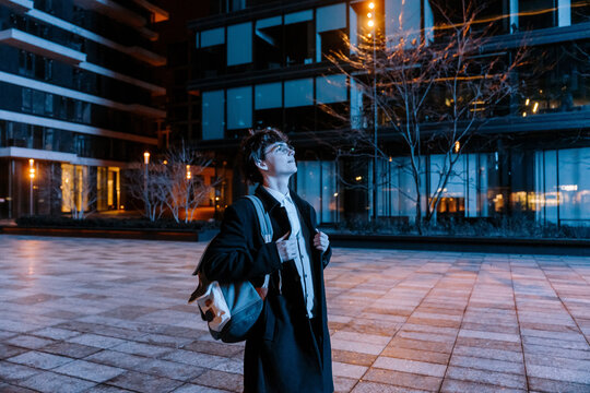 A male intern is standing and looking up on the street