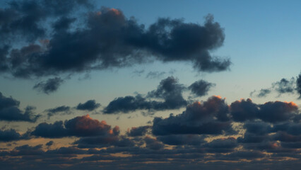 Moody sunset sky over the ocean. Dark clouds illuminated with warm light create a captivating and...