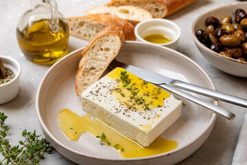 Fresh feta cheese with olive oil , herbs and fresh bread, traditional Greek or Italian food, Mediterranean diet	