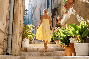 Smiling woman in dress walking in street of Korčula town in Croatia.