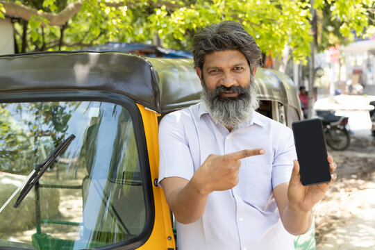 Indian auto rickshaw driver man showing smartphone.
