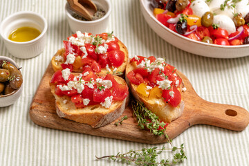 Tomatoes sandwich bruschetta with tomatoes, feta cheese, and herbs, served on a wooden cutting...