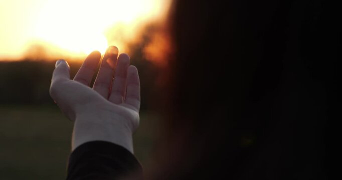 Open palm pointing towards soft light sunset, silhouette hand at sunset symbolizes spiritual awakening and meditation through open palm, awakening of inner peace and harmony