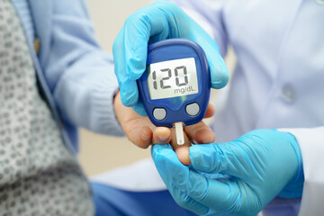 Asian doctor using digital glucose meter for check sample blood sugar level to treatment diabetes.