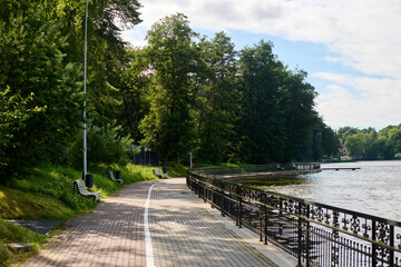 Peaceful lakeside pathway with benches along scenic route, perfect for walking and relaxation. Ideal for nature lovers seeking tranquility and greenery by water