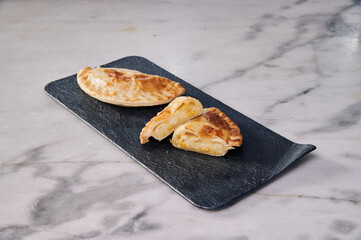 A pastry is cut in half and placed on a black plate. The plate is on a marble counter