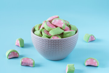 Colored marshmallow with watermelon flavor in a porcelain bowl on a blue background, side view, copy space , high-resolution .