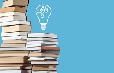 Idea and knowledge. Light bulb with cogwheels illustration over stack of books on light blue...