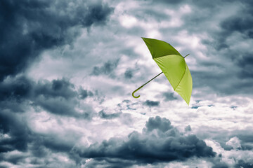 Light green umbrella flying in cloudy sky. Stormy weather