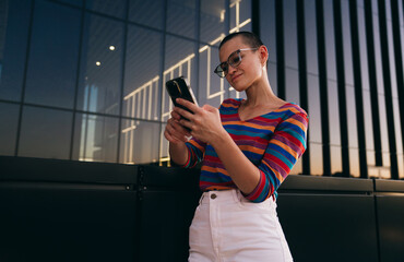 Caucasian woman closely examining phone, checking trading platform or financial dashboard outdoors...