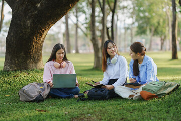 Group of young women working together on school project outdoors, using laptop and tablet, enjoying fresh air and nature
