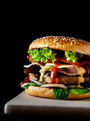 Juicy hamburger with Lettuce and Sauce on Wooden Board