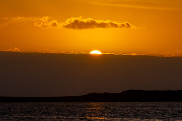 Golden sunset hiding behind clouds over albufeira lagoon in sesimbra, portugal