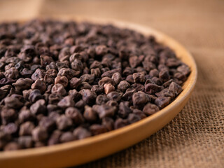 Raw Dark Brown Chickpeas (Kala Chana) on a rustic wooden table. Dry Balck chickpea (ceci neri) background close up.