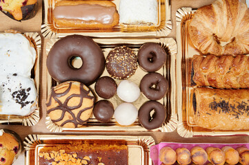 A tray of assorted pastries including donuts, croissants, and muffins. The donuts are chocolate and...