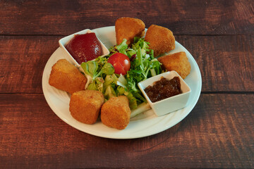 A plate of food with a variety of food items including fried dough, salad, and condiments