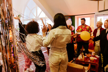 Group of eight friends shouting and cheering with raised hands