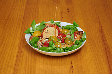 A plate of food with a piece of bread on top. The bread is covered in cheese and tomatoes