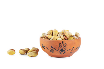 Pile of pistachios in clay bowl isolated on white background.